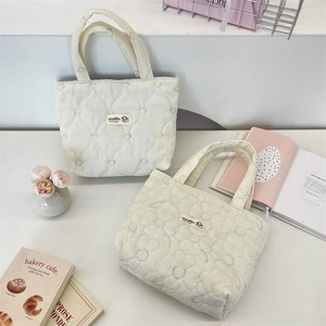 Detailed embroidery of colorful hearts and flowers on white quilted canvas tote bags
