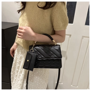 Detail of black embossed handbag with woven handle and matching mini coin purse attachment