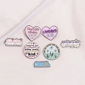 Set of 7 colorful enamel pins featuring Swiftie lyrics on white canvas bag surface