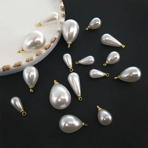 Close-up of white waterdrop faux pearl pendants with gold hooks for DIY jewelry making