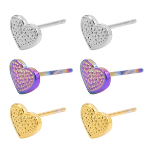 Detailed macro view of heart-shaped steel earrings in silver, gold, and purple finishes