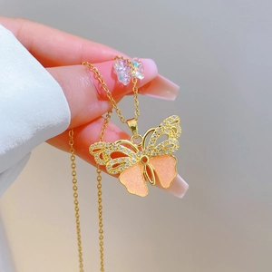 Detailed close-up of a gold butterfly necklace with pink wings and sparkling crystals