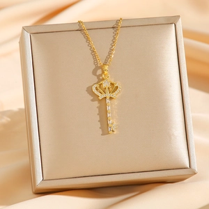 Collier pendentif clé couronne dorée avec zircons sur boîte à bijoux de luxe