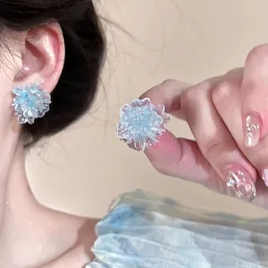 Close-up of translucent blue flower earrings featuring layered resin petals on model