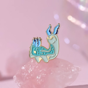 Cute fantasy sea slug enamel pin with star patterns and blue flowers on a pink background