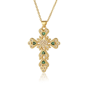 Macro detail of golden cross necklace with heart element and green gemstone inlay