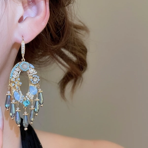 Primo piano di una modella che indossa eleganti orecchini con zirconi blu e grigi