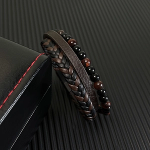 Detail of multi-layer woven leather bracelet with red tiger eye beads on black gift box