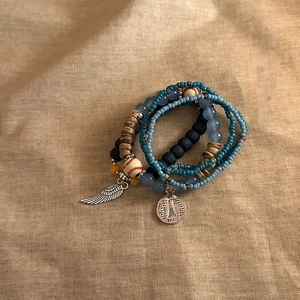Detail of bohemian multilayer beaded bracelets with Eiffel Tower and wing charms