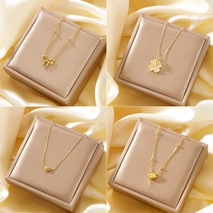 Selection of four 18K gold plated heart and bow necklaces on soft silk background