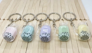 Macro shot of assorted colorful bubble tea keychains with liquid and pearls on wood base