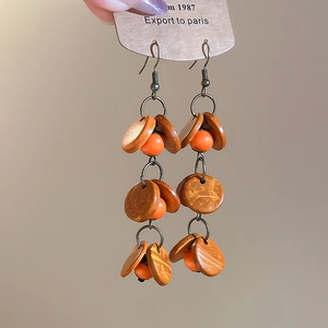 Détails des boucles d'oreilles bohèmes avec perles orange et disques en bois brun