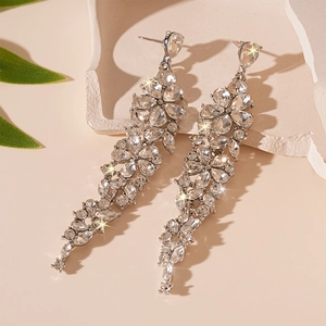 Close-up of silver tassel earrings with flower shaped crystals on stone surface