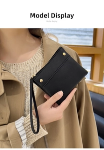 Minimalist black faux leather coin purse with golden studs held by a model