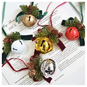Close-up of velvet bows and pine cones on festive Christmas bells over vintage paper