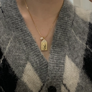 Close-up of gold religious Virgin Mary pendant necklace with a white pearl on a model