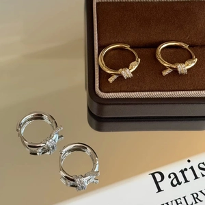 Boucles d'oreilles créoles nouées or et argent avec zircons sur coffret à bijoux