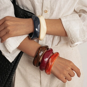 Détail de bracelets en résine marbrée de différentes couleurs portés sur le bras d'un modèle