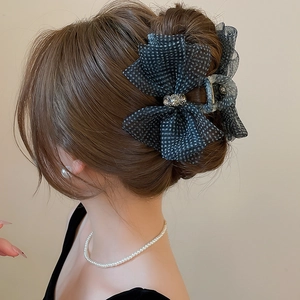 Detailed close-up of a black mesh polka dot bow hair claw clip with crystal accents