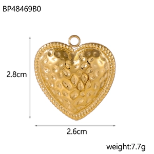 Macro detail of gold-tone heart pendant with unique hammered texture and dimensions