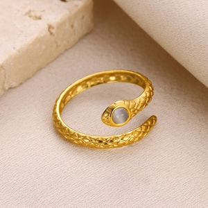 Macro detail of golden snake ring featuring scale texture and grey round gemstone inlay