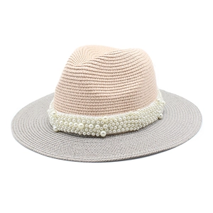 Close-up of elegant two-tone straw hat featuring luxurious pearl band detail