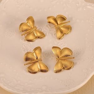 Elegant 18K gold-plated dragonfly earrings displayed on a decorative white porcelain dish