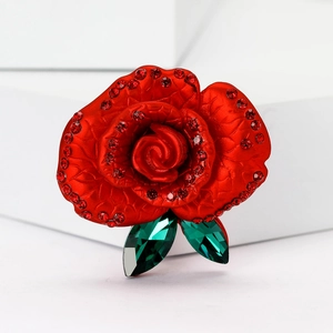 Elegant red enamel rose brooch with sparkling crystals and green leaves on white background