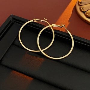 Macro view of gold hoop earrings with smooth metallic finish and hinged closure