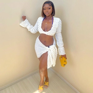 Chic white two-piece set featuring long sleeve crop top and matching mini skirt in seersucker fabric