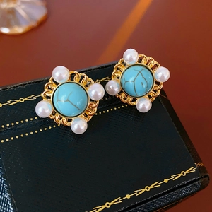 Detail of vintage gold earrings with turquoise stone and white pearls in a retro jewelry box