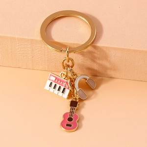 Detailed shot of music-themed keychain featuring pink enamel guitar, keyboard, and headphones