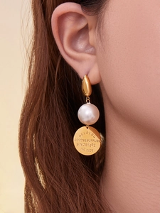 Détail de boucles d'oreilles en perles plaquées or 18K avec disque gravé sur un modèle