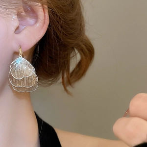 Detail of gold hollow petal drop earrings with mesh texture on model for women