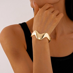 Polished gold wavy cuff bracelet shown on model with minimalist geometric curves