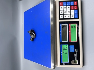 Dettaglio di statuina di gatto in resina su bilancia digitale che mostra il peso di 27,5g