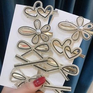 Detailed view of hair clips with faux pearls and rhinestones on gold alloy base