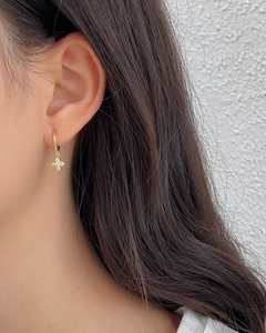 Close-up of woman wearing golden clover drop hoop earrings with sparkling crystal stones