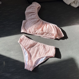 Detailed view of pink one-shoulder ruffle bikini with textured pleats and dotted fabric