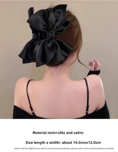 Dettaglio di un grande fermaglio per capelli in raso nero che mostra trama e lucentezza