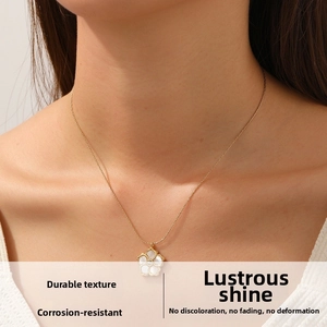 Close-up of a gold-plated necklace with a white flower pendant and diamond accent on neck