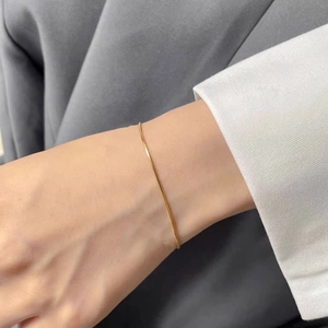 Close-up of minimalist gold snake chain bracelet on a wrist for layered styling
