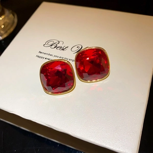 Close-up of vintage flower pearl earrings with red square gemstone in gold frame on gift box