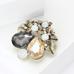 Vintage gold flower brooch with crystal gems and champagne rhinestones on white platform