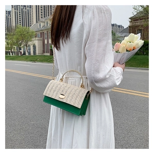 Detail of green crossbody bag with woven flap and gold ring handle in street style