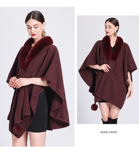 Detail of burgundy knitted poncho with faux rabbit fur collar and playful pom-pom hem