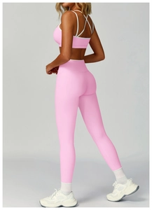 Dettaglio del set yoga rosa con reggiseno sportivo incrociato e leggings a vita alta