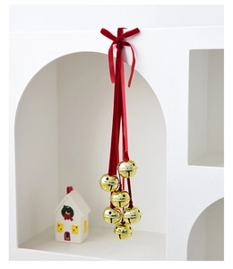 Detailed view of six golden Christmas bells with red ribbons on a white arch display stand