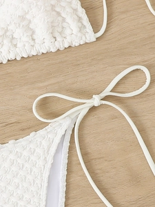 Detailed macro view of white seersucker fabric texture and side tie bow on the bikini