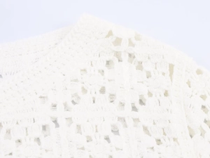 Close-up of white crochet knit top showing intricate hollow patterns and fine textures